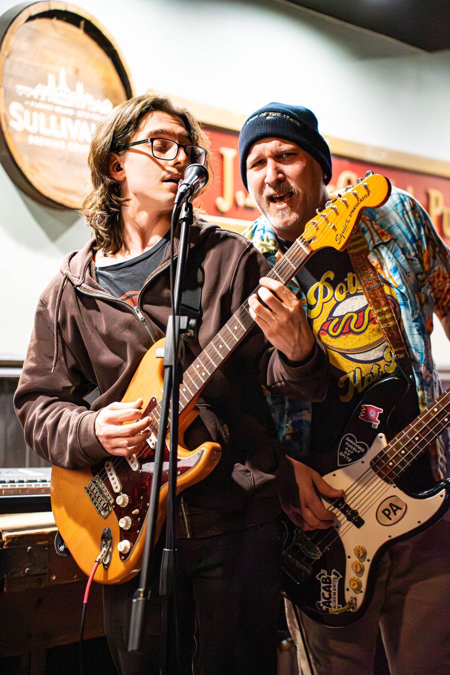 Musicians performing with guitars on stage under bright lighting.