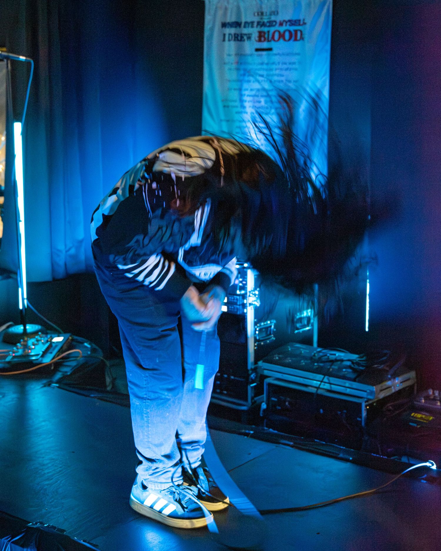 Performer silhouetted against blue stage lighting during dramatic live show moment.