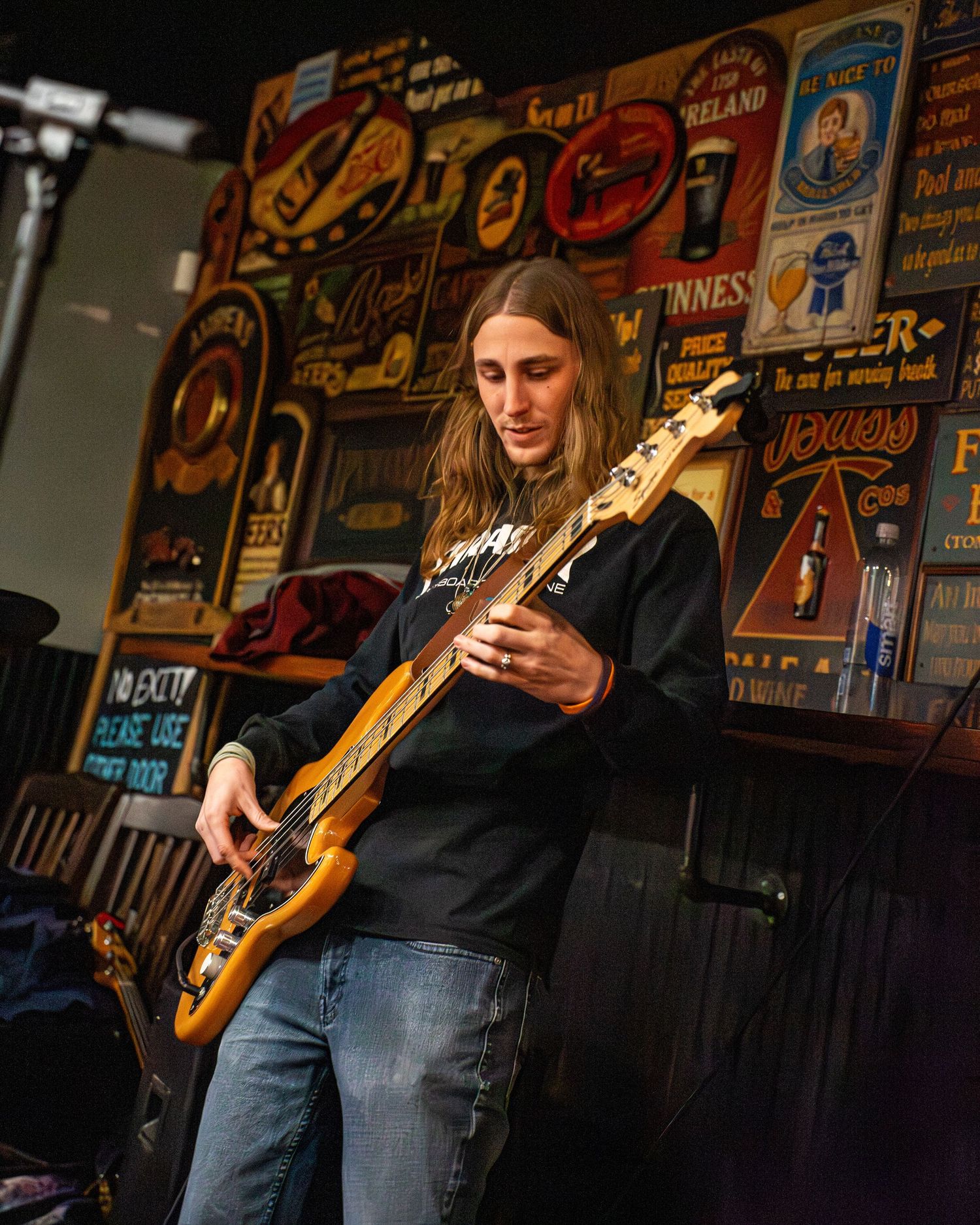 Guitarist performing against wall decorated with vintage music posters and memorabilia.