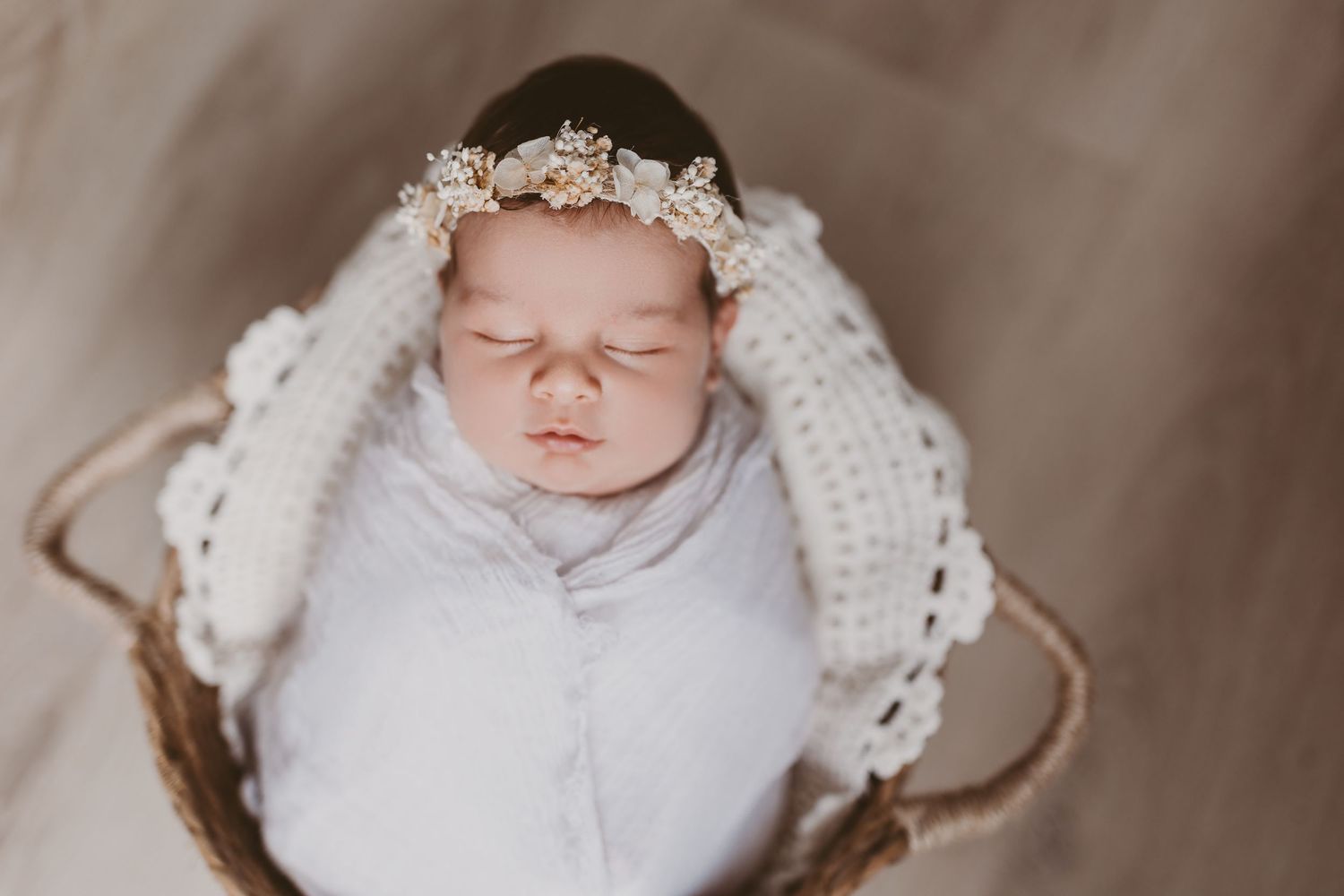 Newborn baby sleeping peacefully in white bonnet.