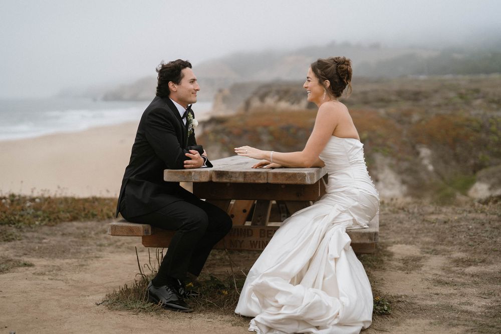 A wedding couple shares tender moments on a coastal cliff overlooking the ocean.