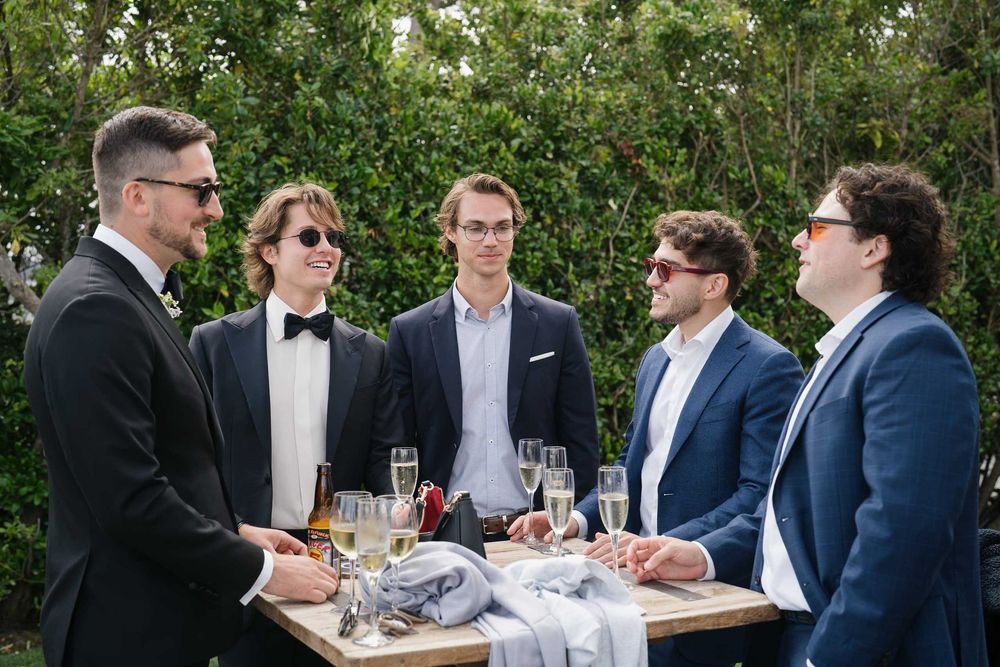 A group of men in formal attire having a conversation at an outdoor gathering.