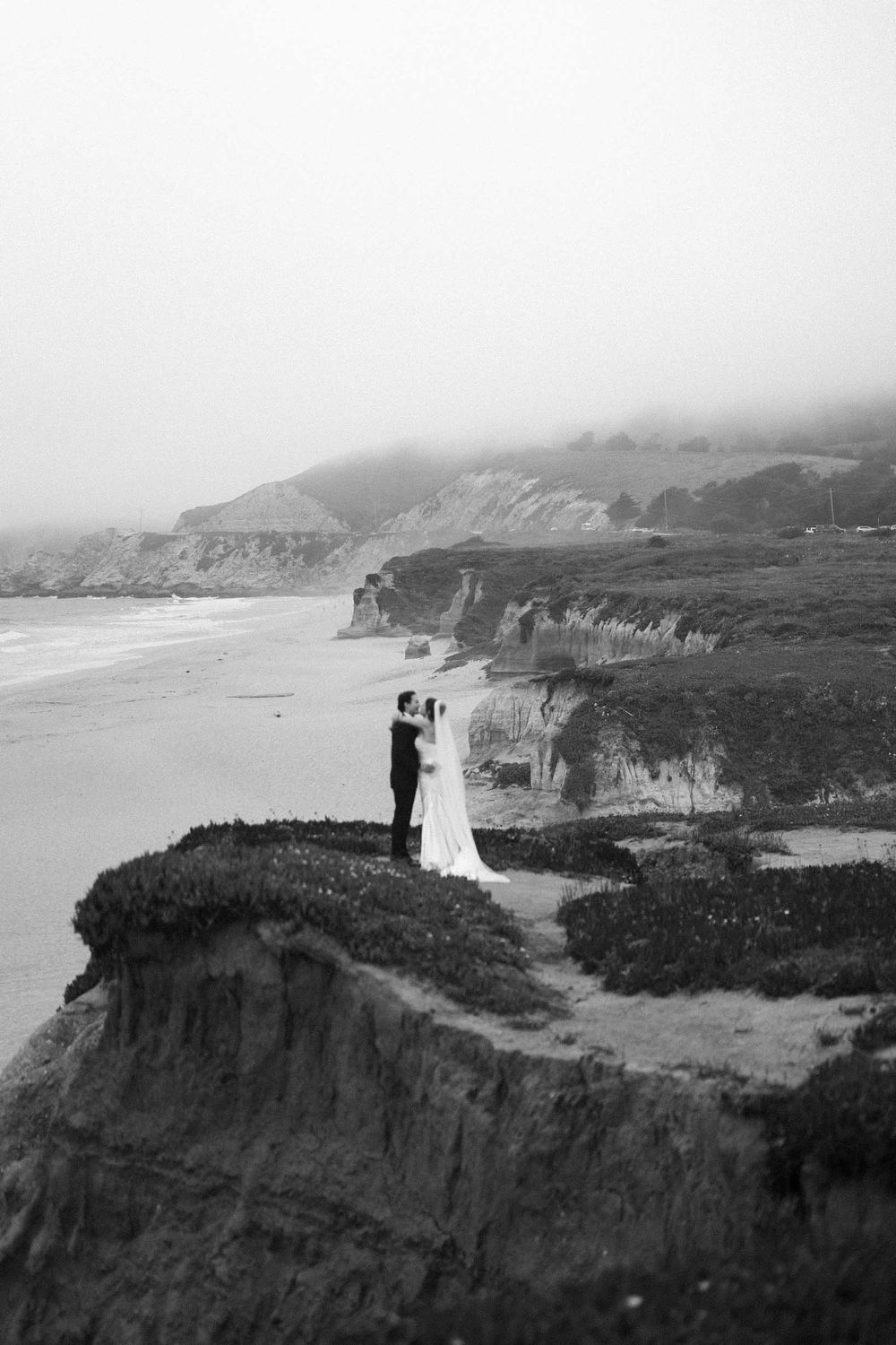 Dramatic black and white coastal landscape with cliffs overlooking the ocean on a misty day.