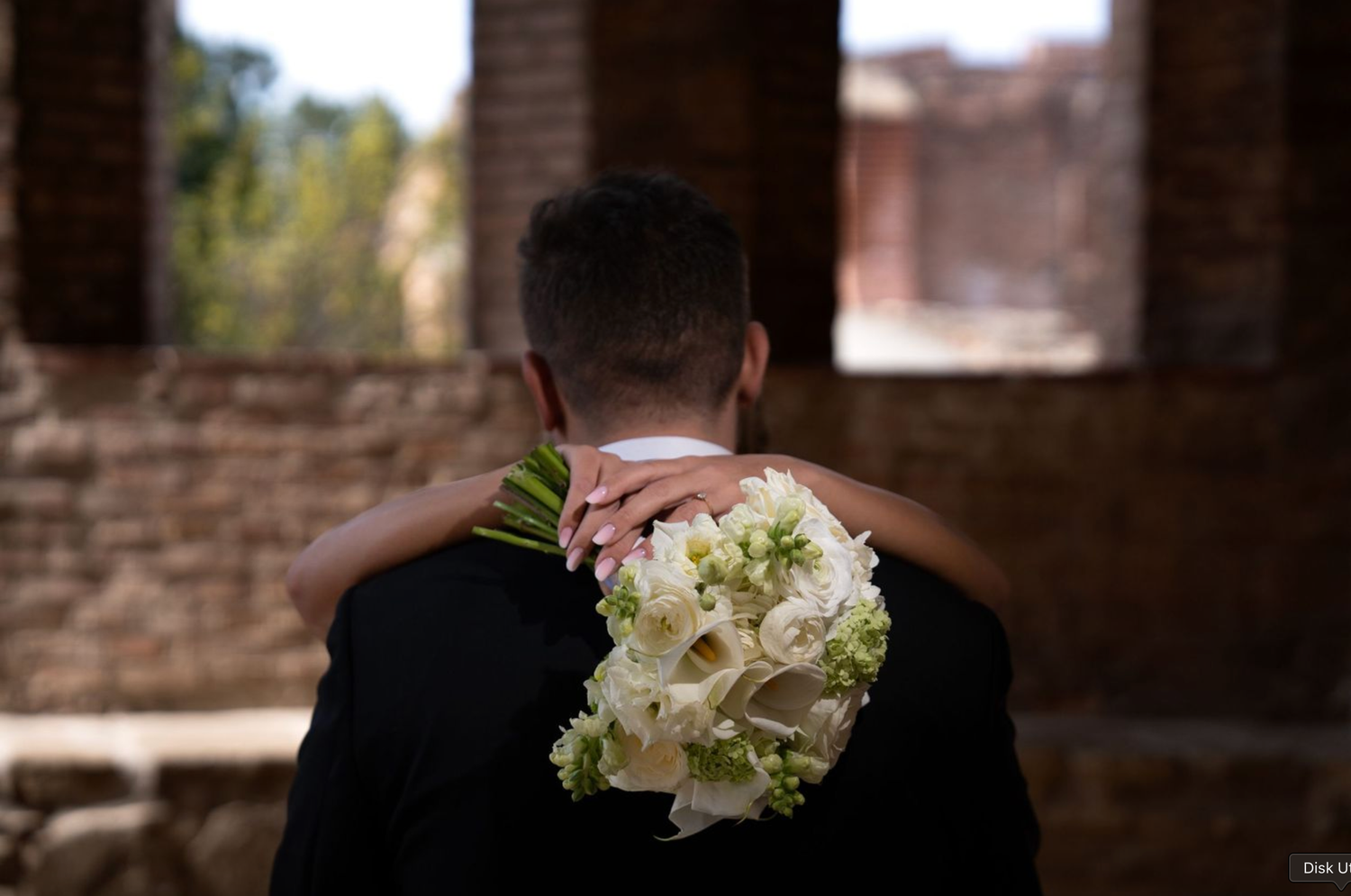 Wedding details showing white floral bouquets in stone archway setting.