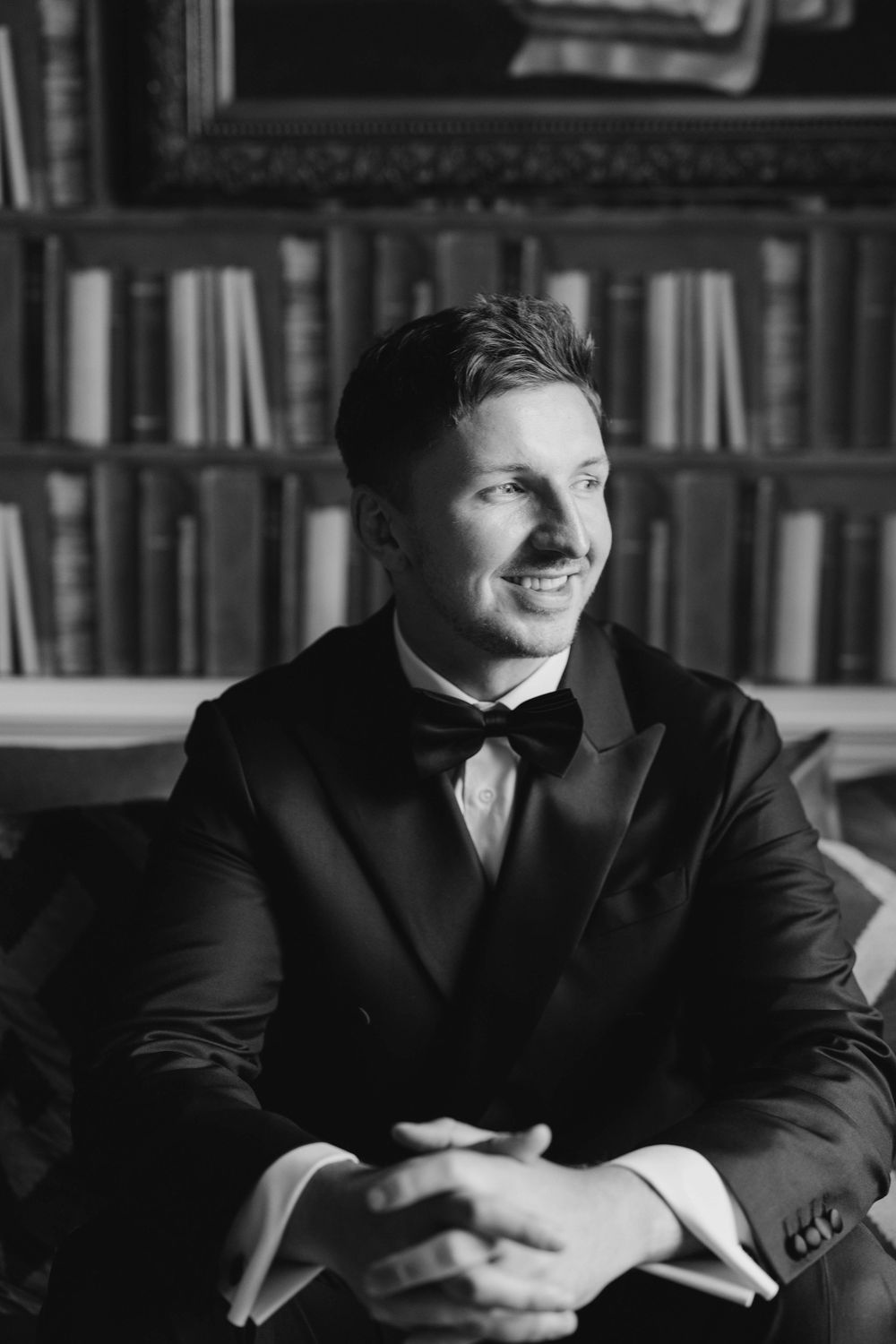 Black and white portrait series of groom in library setting showing contemplative expressions.