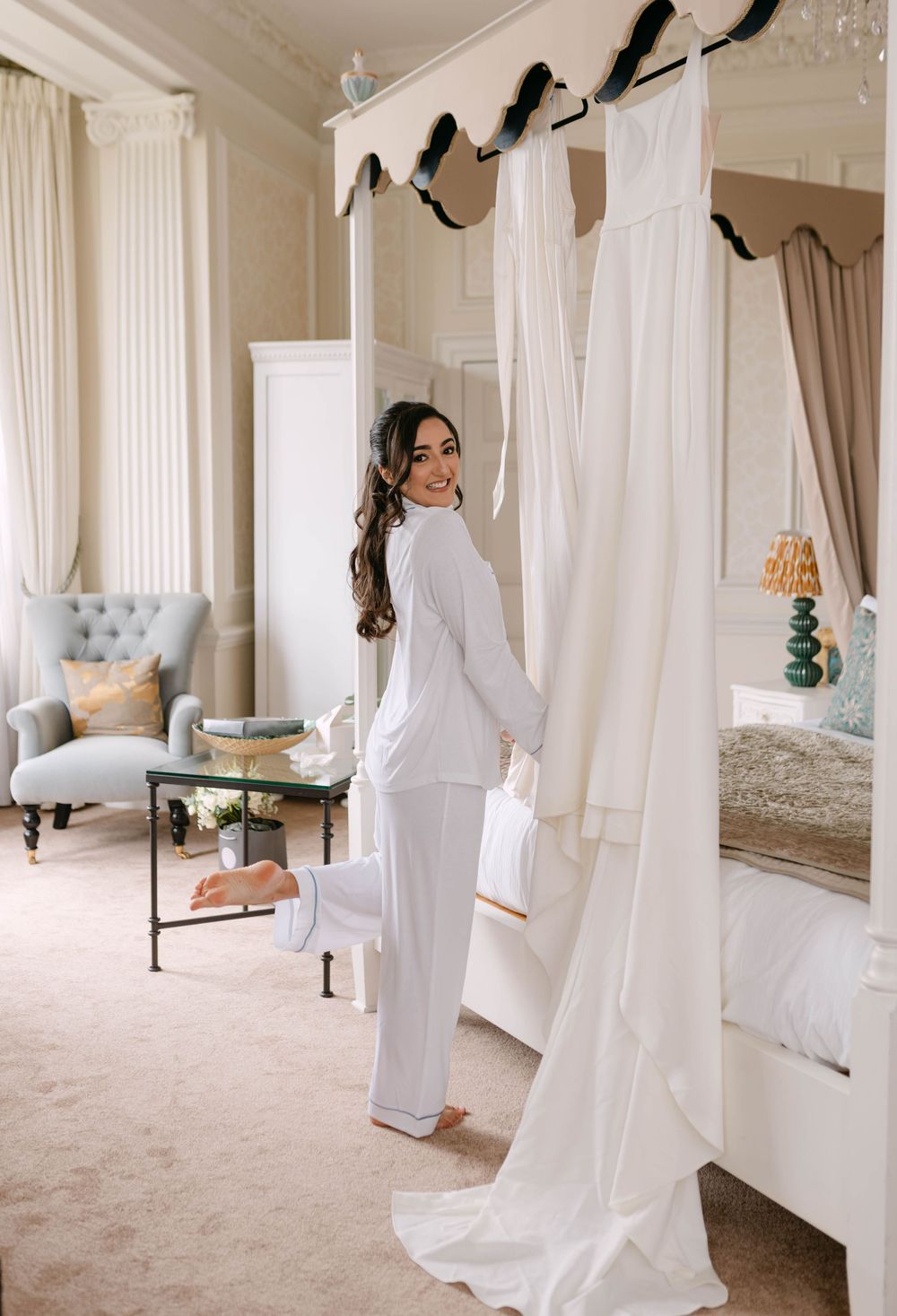 Spacious white bedroom with draped curtains and elegant furniture.