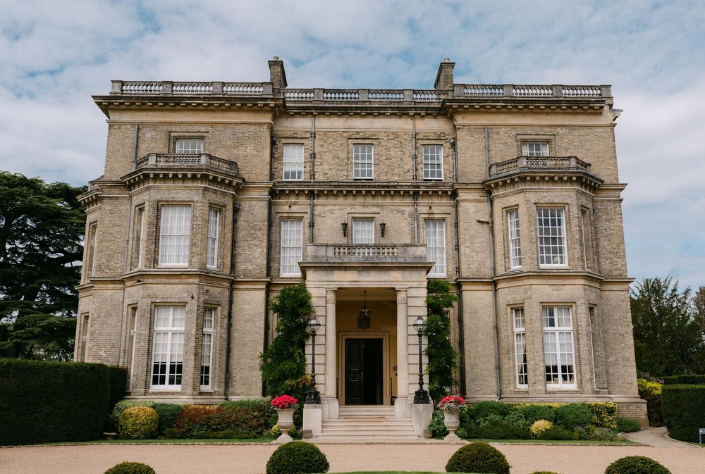 Elegant stone mansion with symmetrical windows, grand entrance, and manicured gardens.