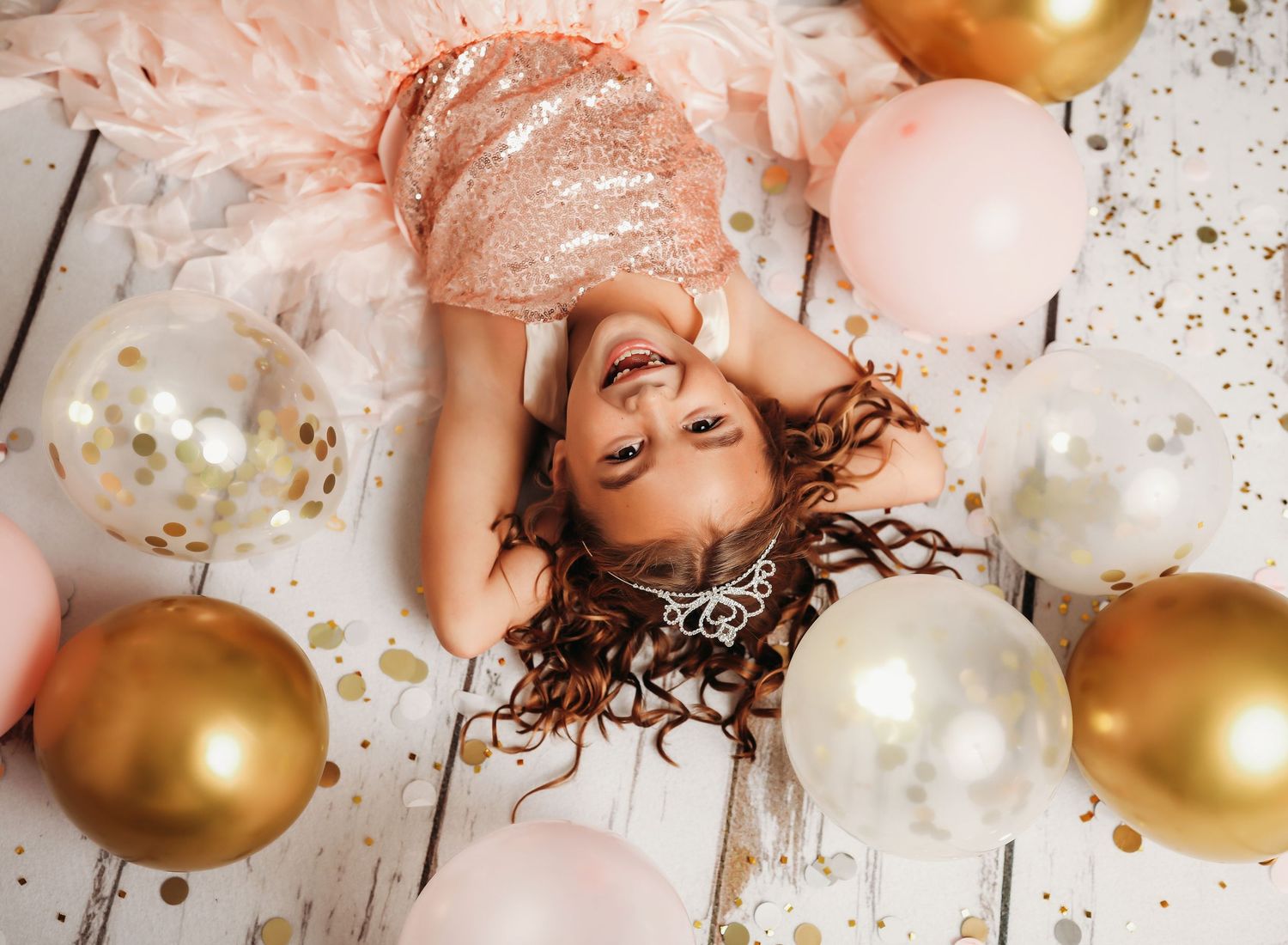 Pink and gold balloons scattered on a rustic wooden floor with confetti.
Best child's photographer in Illinois