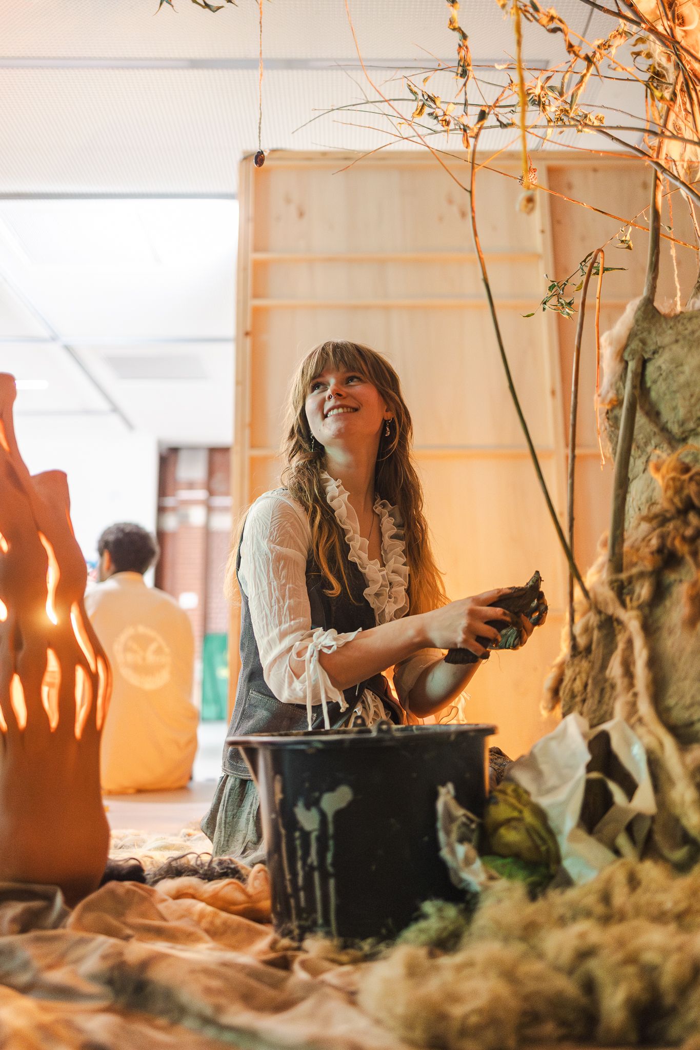Artist working with clay and natural materials in a sunlit studio space creates an organic sculpture installation.