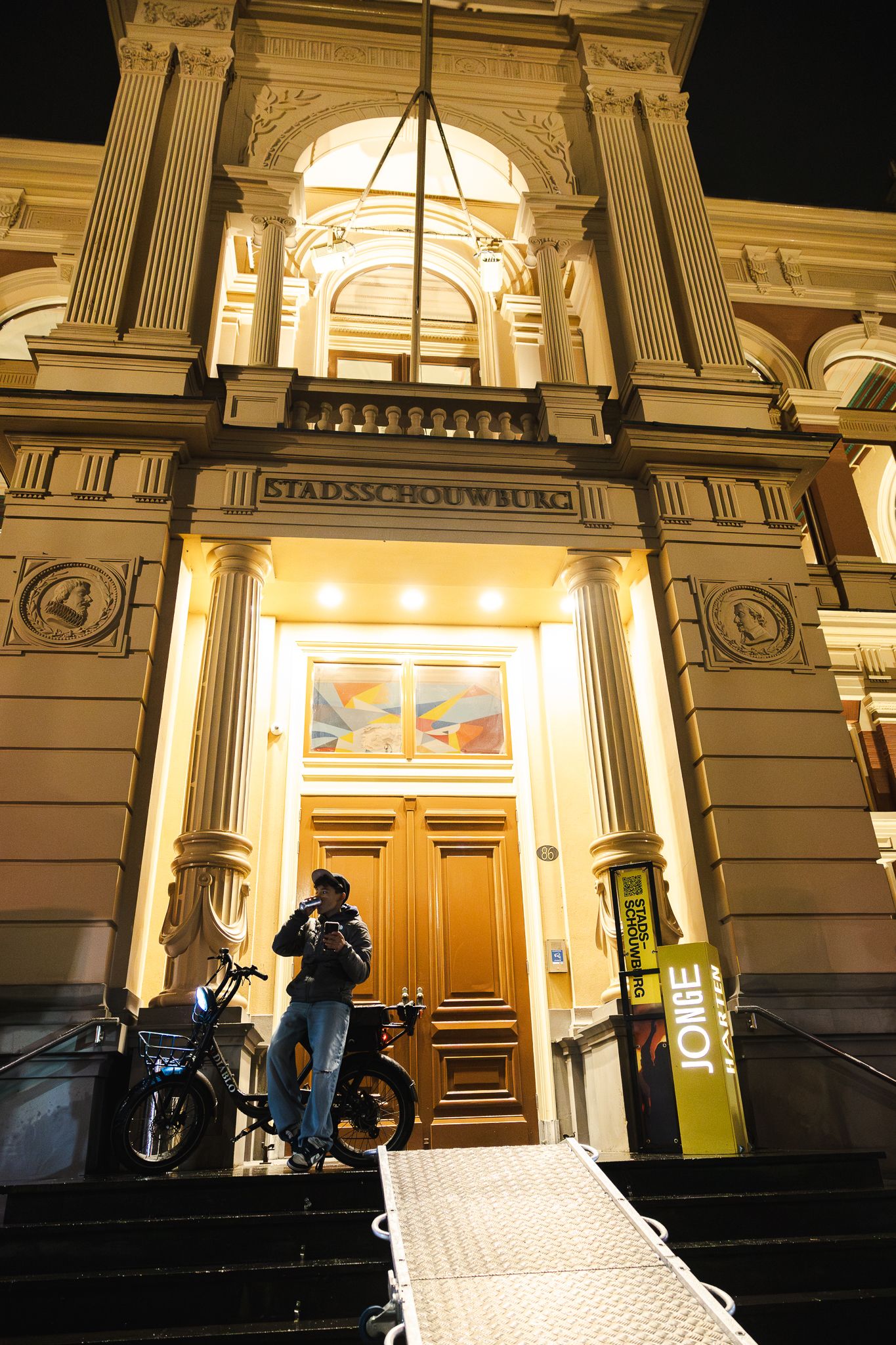 Architectural details of illuminated building entrance with ornate columns and doorway at night.