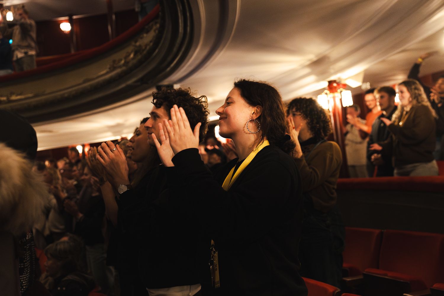 A crowd of people dancing and celebrating in a dimly lit venue with decorative lighting overhead.