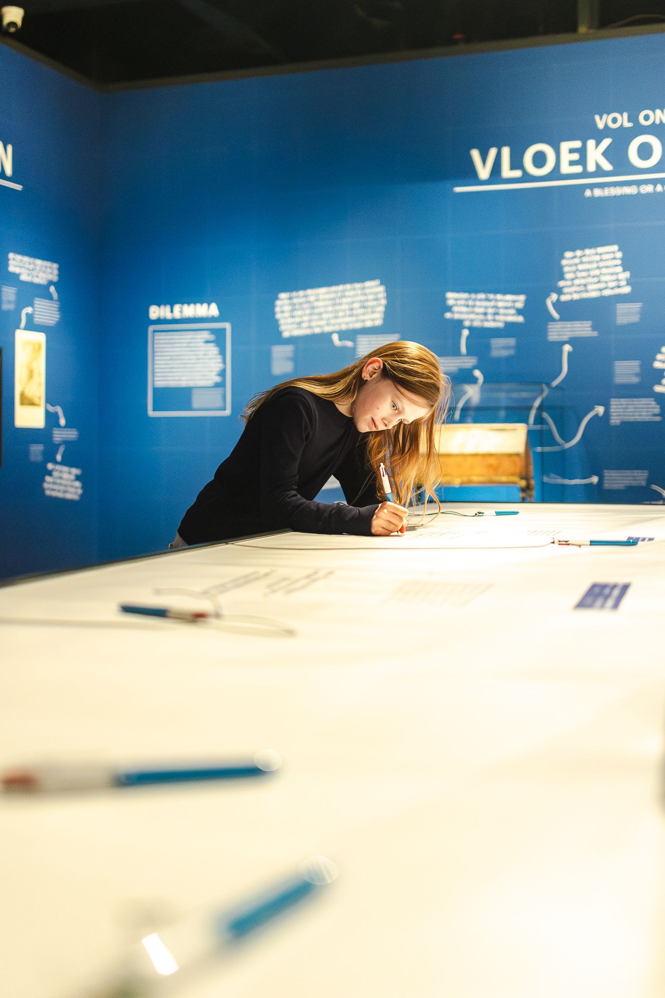 Museum visitor studies information displayed on bright blue wall with white text in exhibition space.