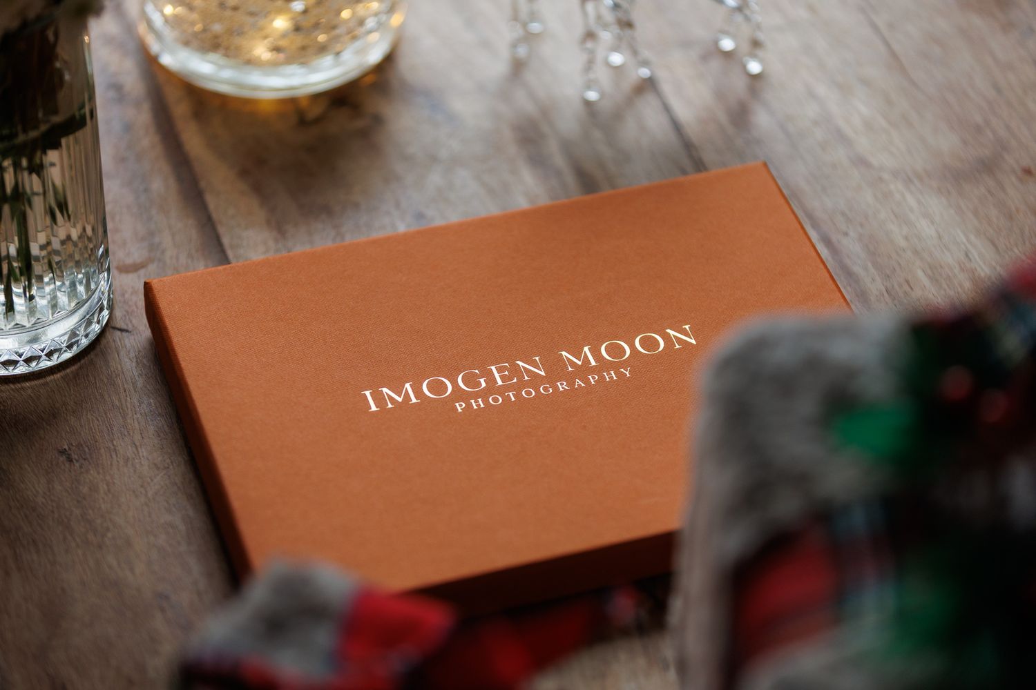 A rustic wooden table displays a collection of brown leather books and a glass of golden liquid.