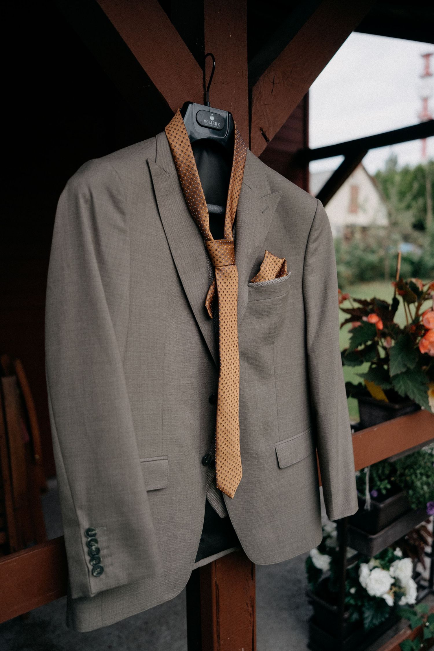 A gray suit jacket with tan tie and pocket square hanging on display.