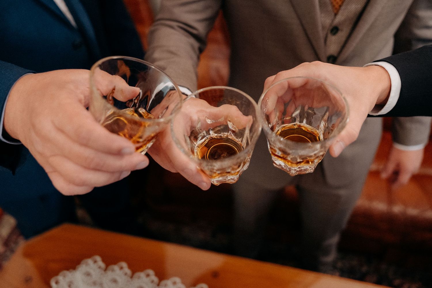 Three glasses of amber-colored spirits being toasted together.