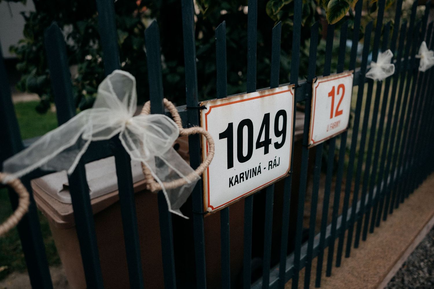 Race number 1049 attached to black metal fence with white bow decoration.