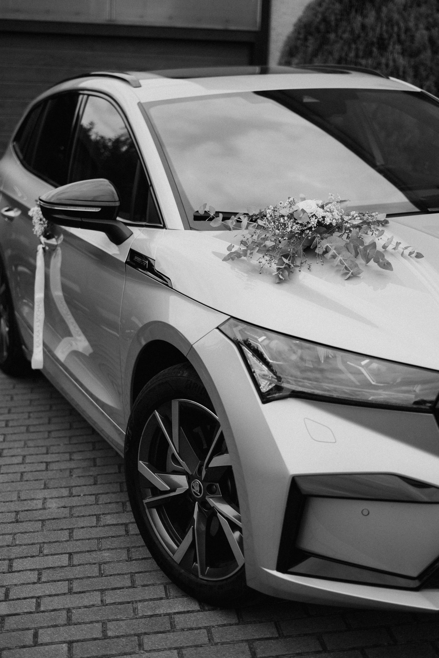 White luxury sports car decorated with floral arrangements for a wedding celebration.