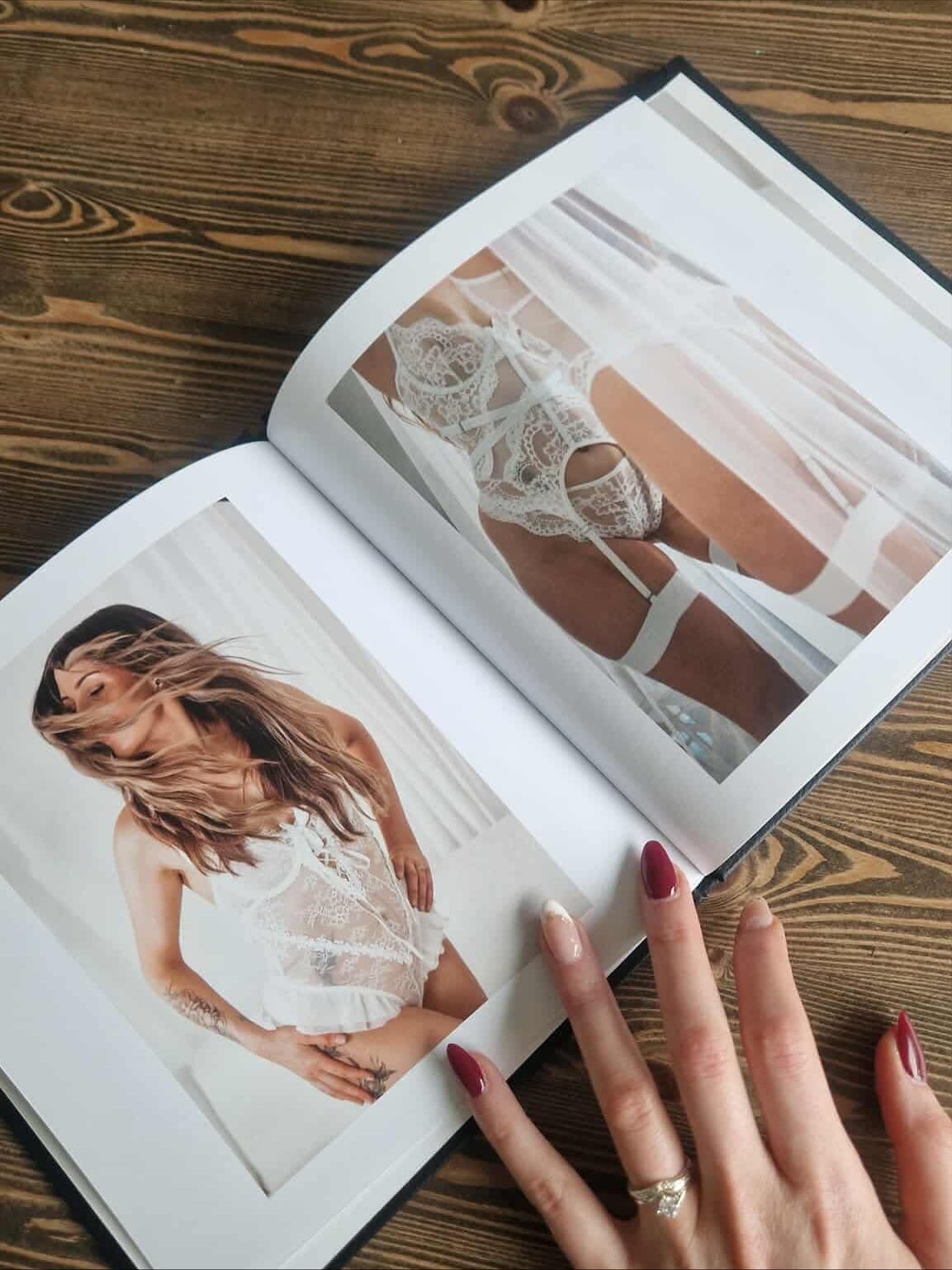 Hands turning pages of a wedding photo album on wooden surface.