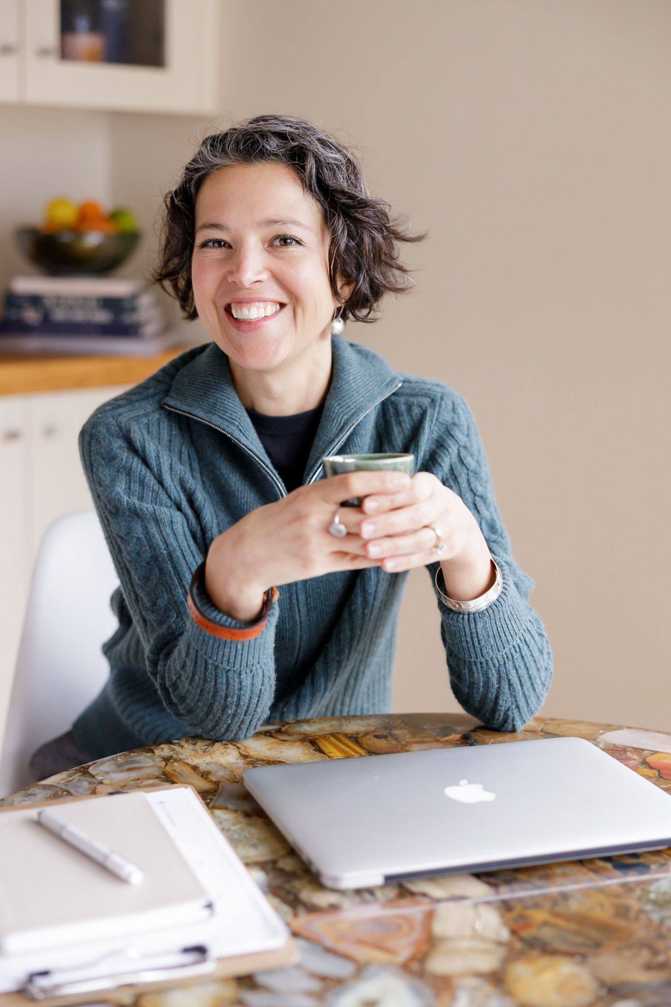 female cycle hormone coach sitting at home desk with computer and mug in hand for lifestyle headshot in Seattle, WA