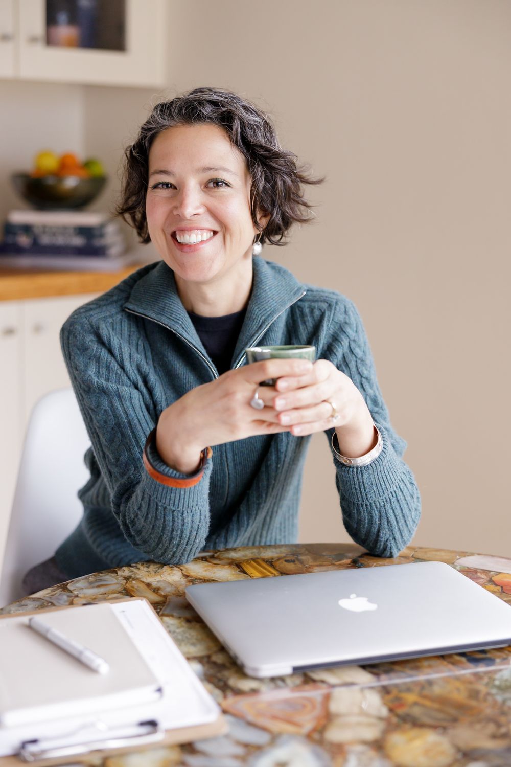female cycle hormone coach sitting at home desk with computer and mug in hand for lifestyle headshot in Seattle, WA