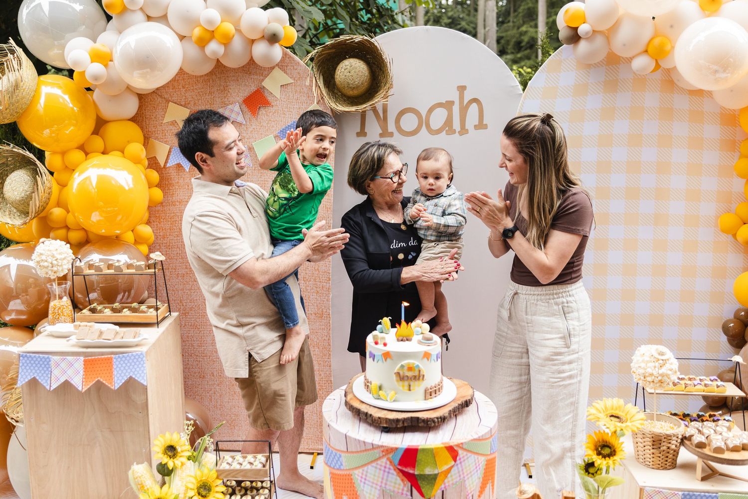 A peach and orange balloon decorated party with dessert table and guests celebrating a special occasion.