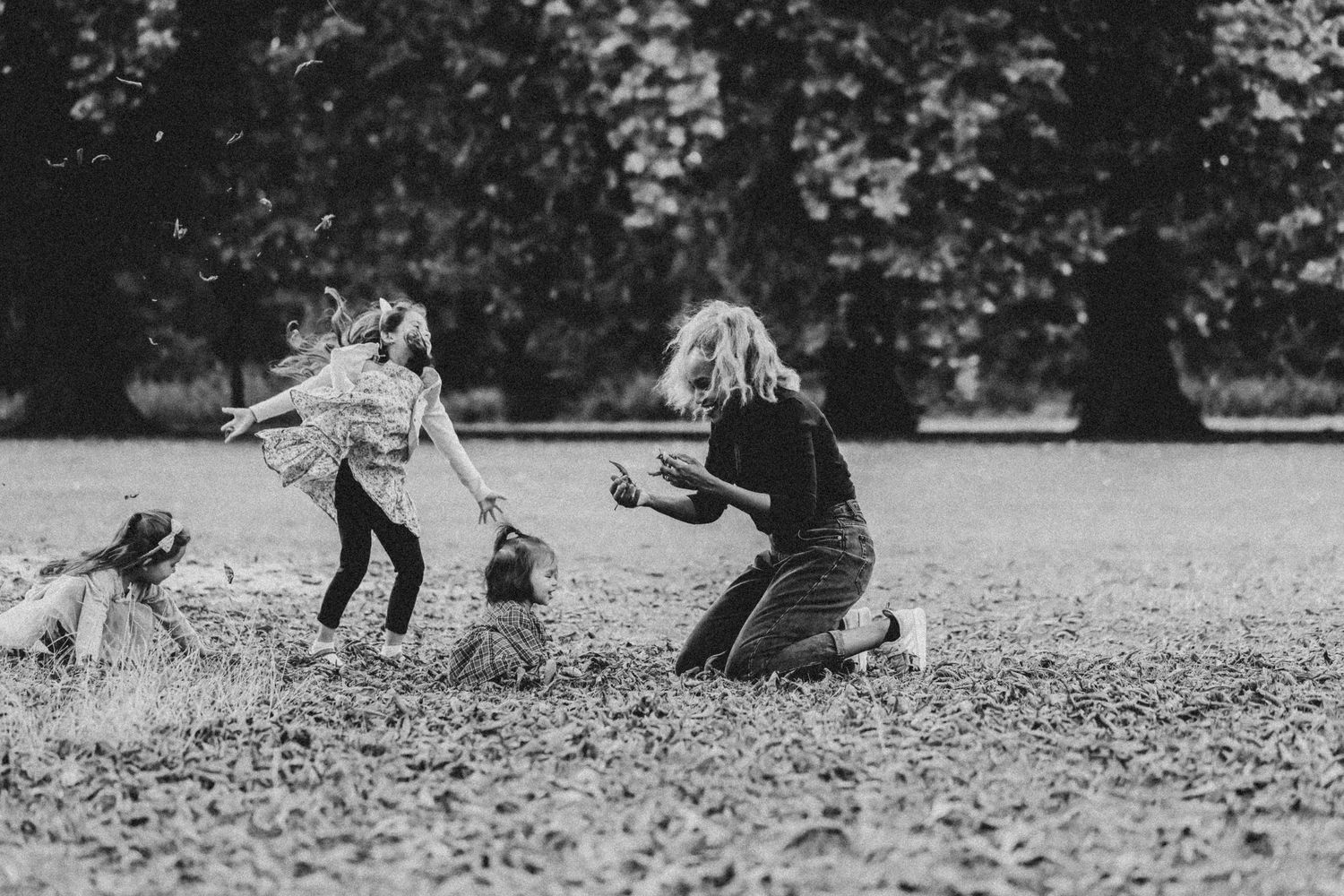 A sequence of black and white photos showing people playing and throwing autumn leaves in a park.