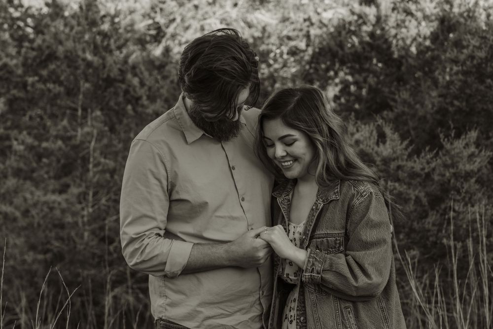 A black and white photo captures an intimate moment between a couple outdoors.