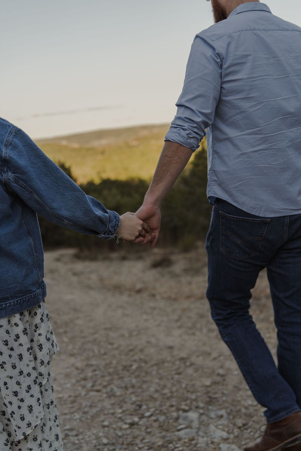 Close-up view of two people walking together on a desert trail.