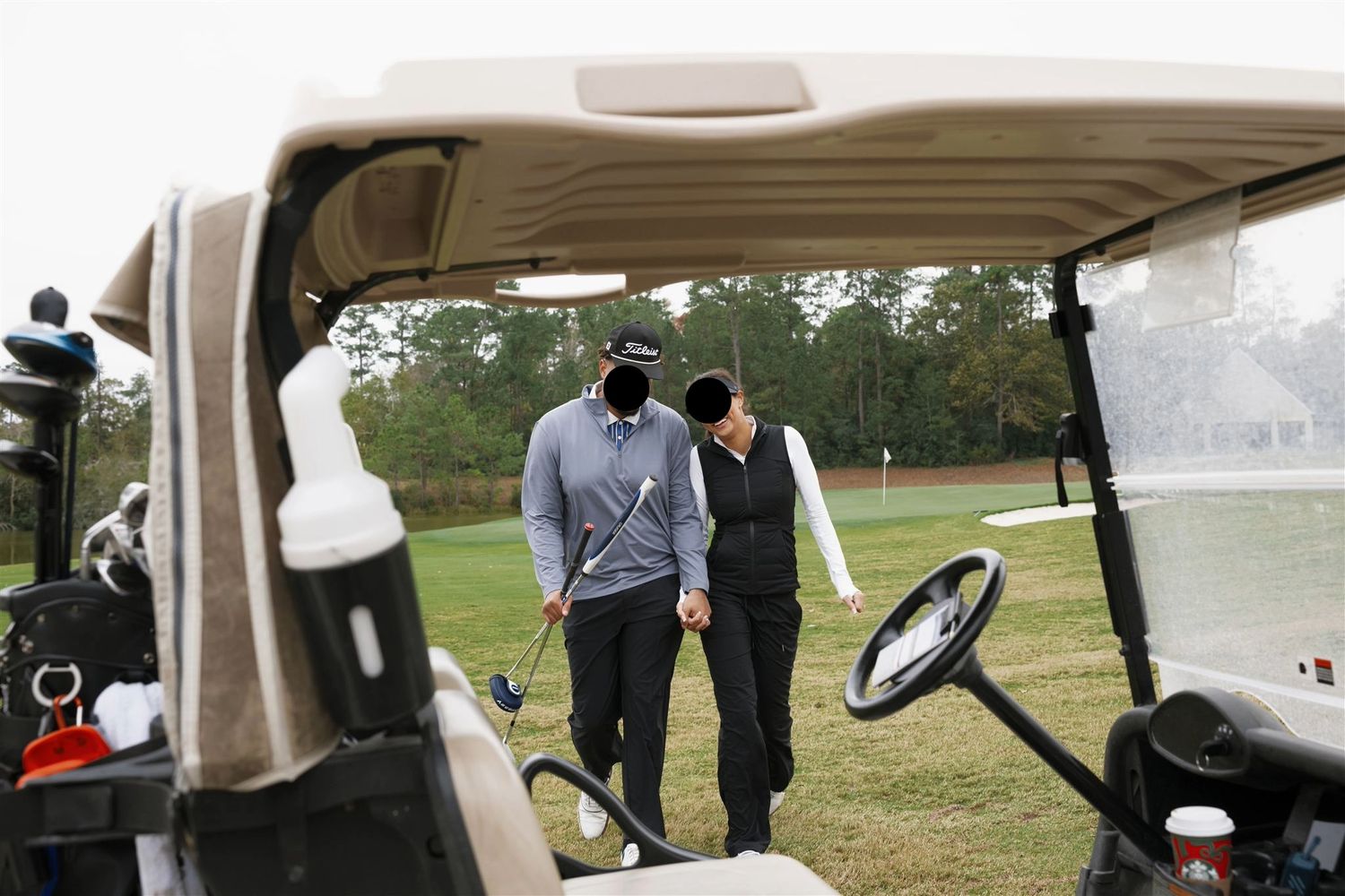 An image of a couple holding hands and walking towards a golf cart during an overcast day.