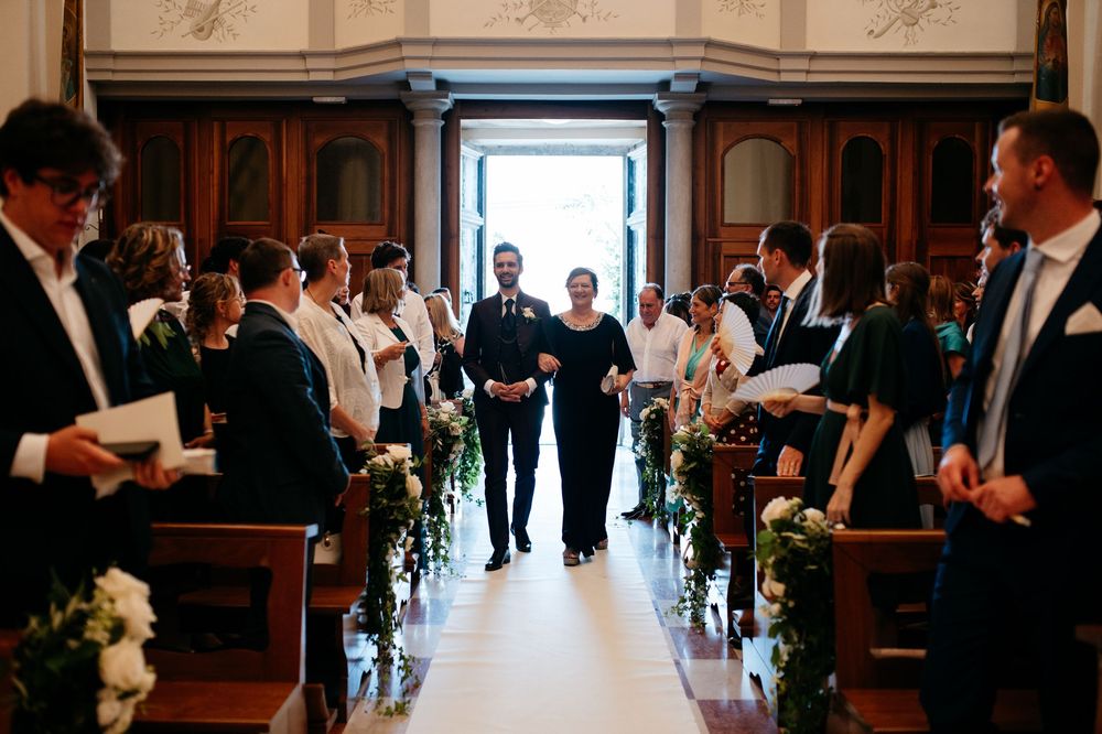 Wedding ceremony guests gather in an elegant wood-paneled room with ornate architectural details.