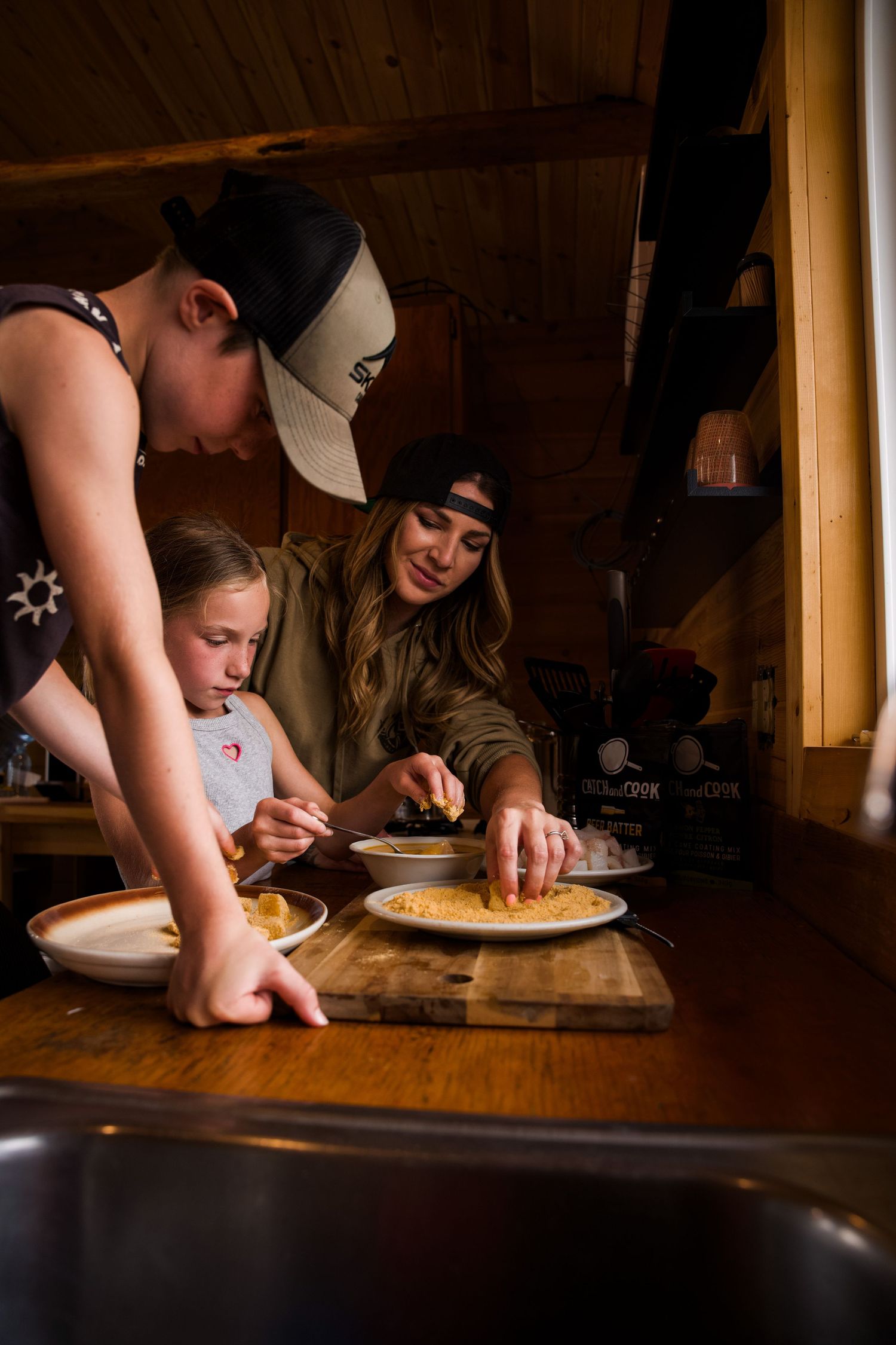 People gathered around a table preparing food in a cozy cabin interior.