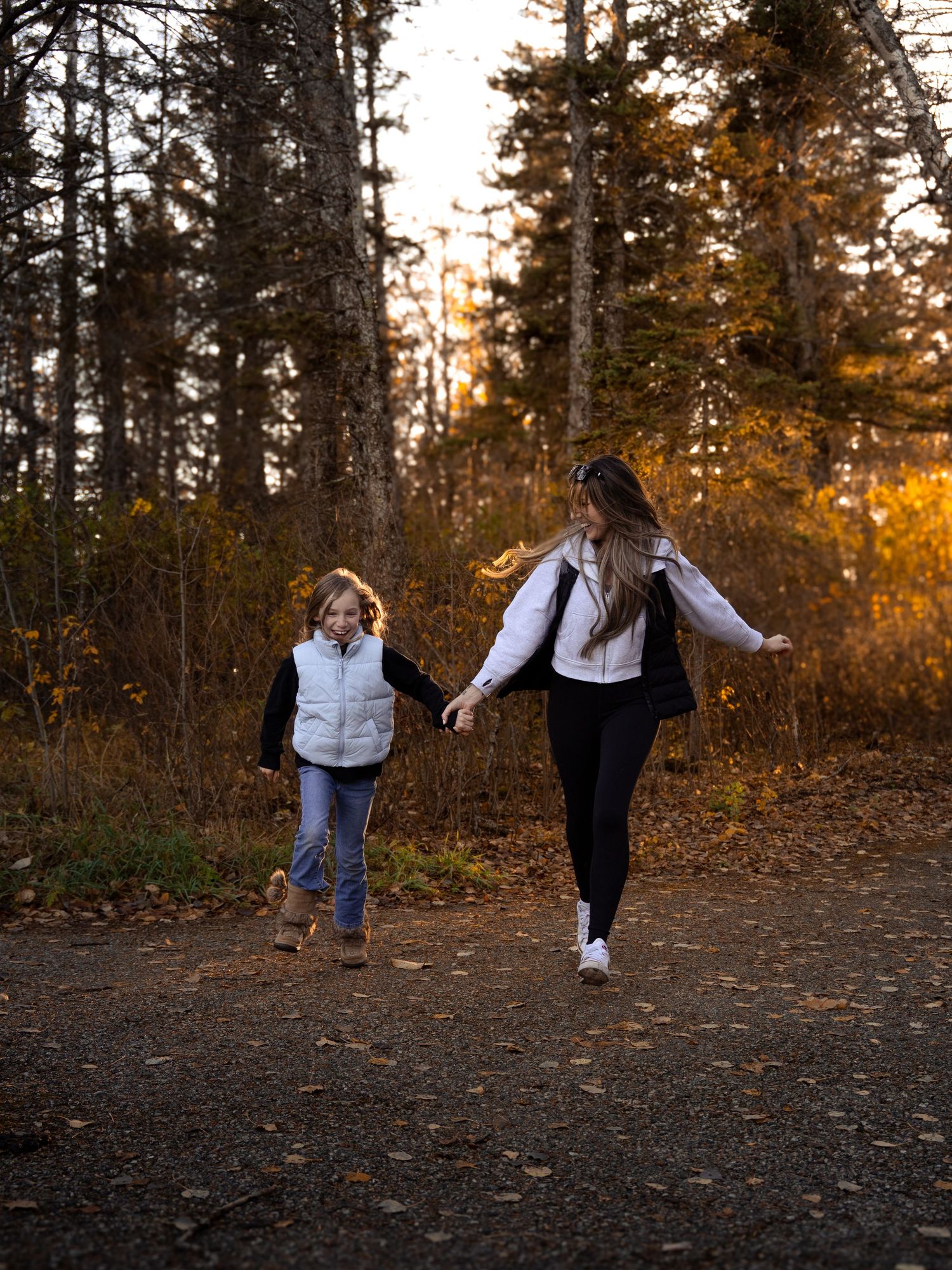 Two people walking together on forest path during golden autumn sunset.