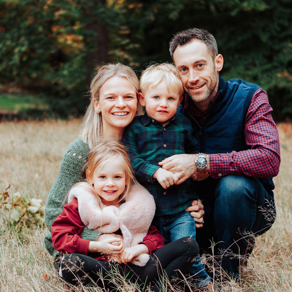 Cosy moment of a family smiling for the camera in a meadow.
