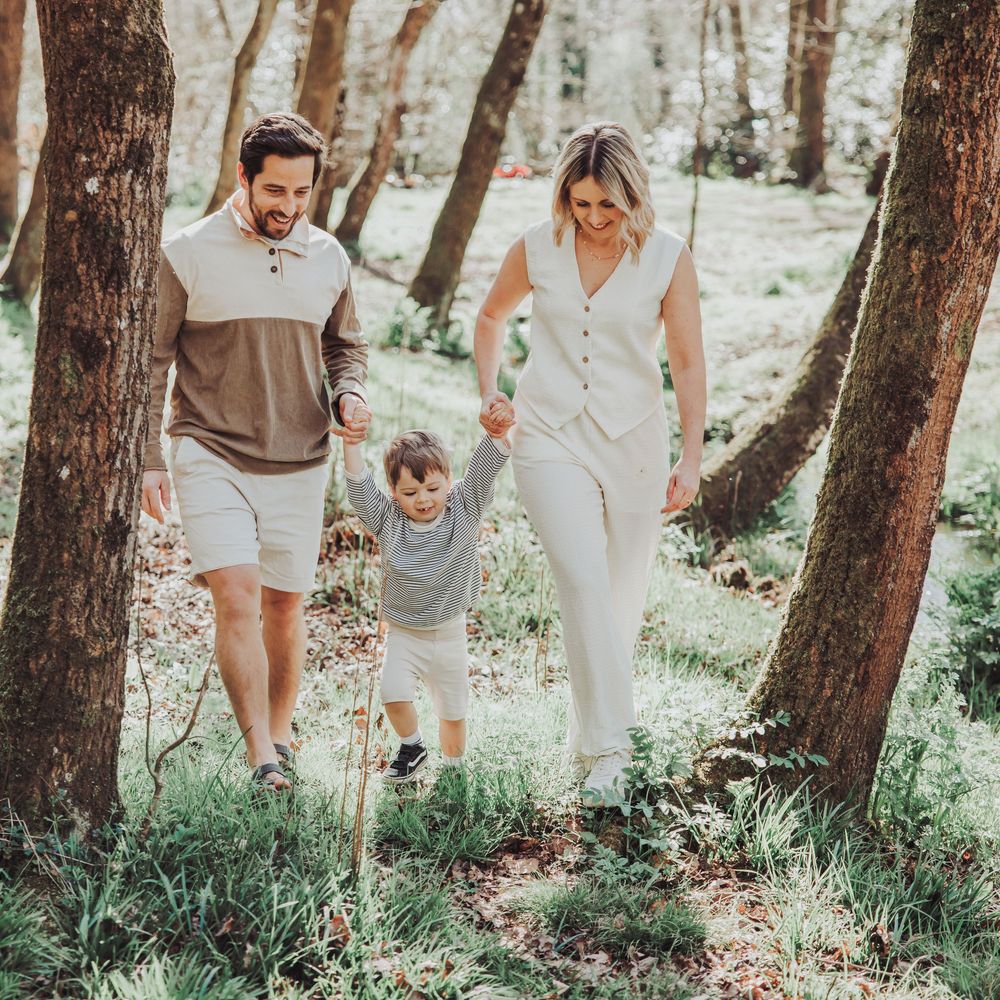 Couple walking with their son through a woodland.  The image is a natural shot of the family holding hands