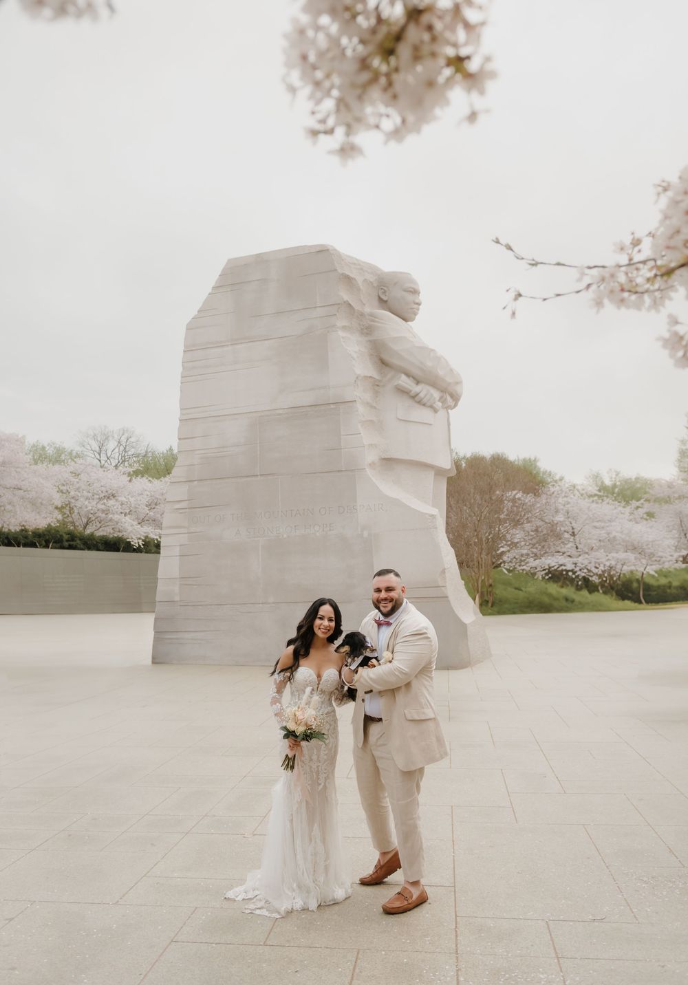 A wedding couple poses at the MLK Memorial in Washington DC during cherry blossom season.