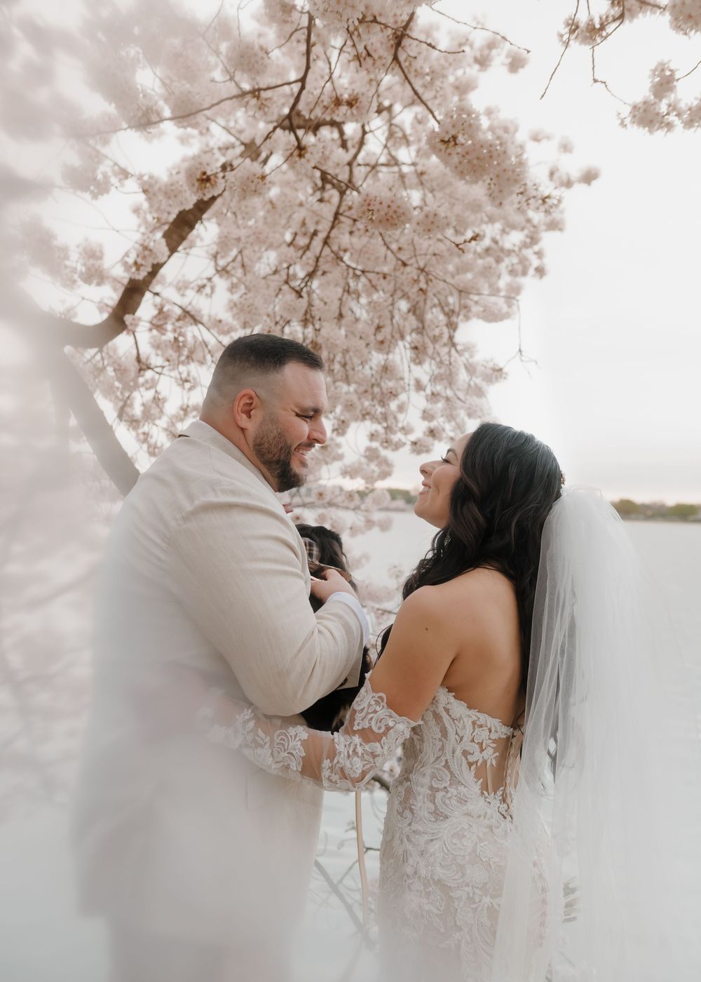 An intimate wedding moment captured under blooming cherry blossom trees.