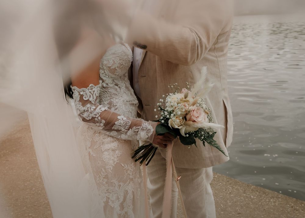 Close-up wedding photos showing details of a lace dress and tender embraces by the water.