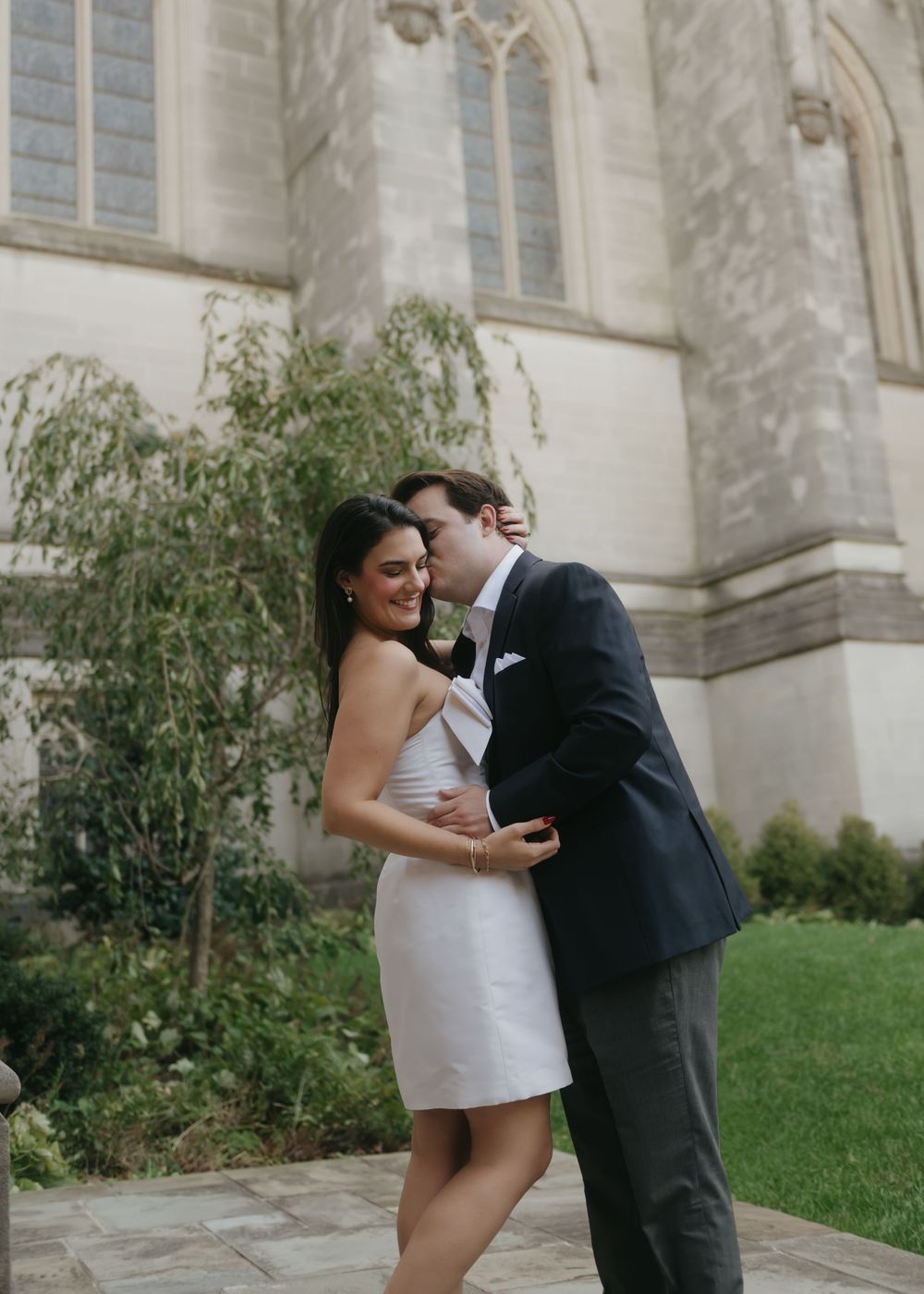 A wedding photoshoot sequence outside a stone church building with landscaped grounds.