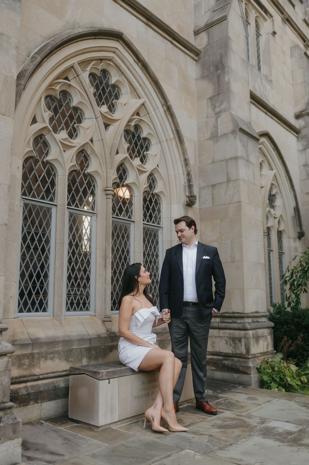 Couple shares candid moments against Gothic architecture with leaded glass windows.