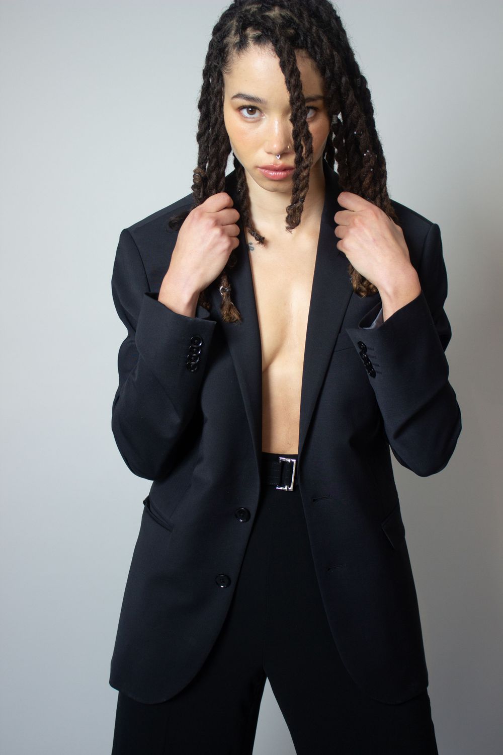 Minimalist fashion portrait in oversized black blazer with braided hair.