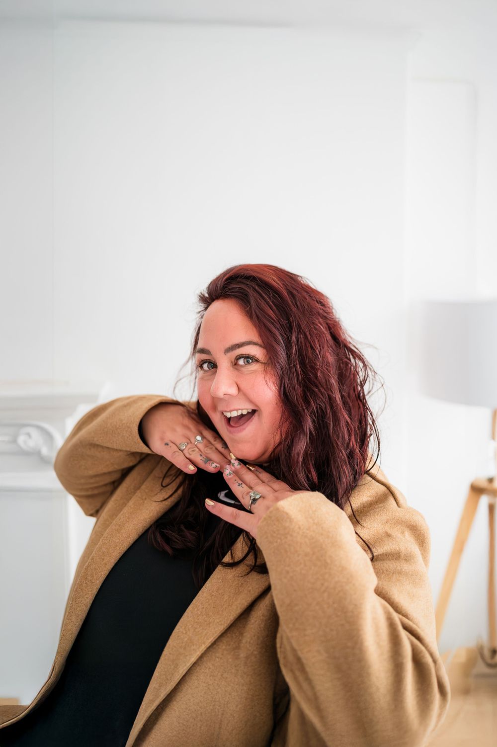 a happy photographer lady posing playfully in a white room
