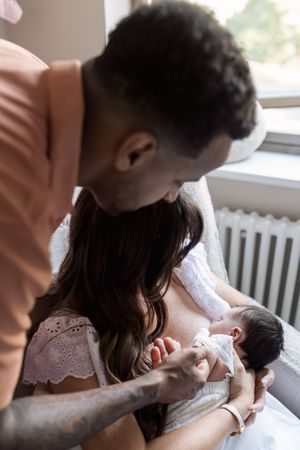 Intimate feeding session captured in soft natural light by a window.