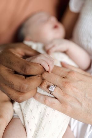 A close-up sequence of hands placing a diamond engagement ring on a finger against a white background.