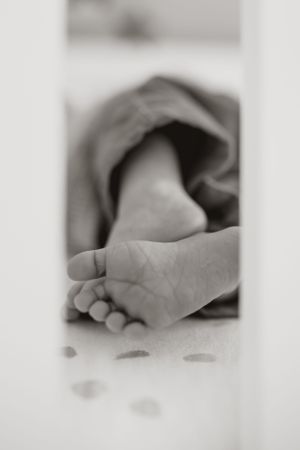 Black and white close-up photo of a tiny baby foot peeking out from under soft fabric.