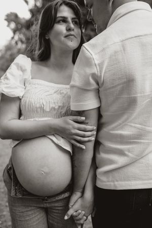 A series of black and white maternity photos showing a pregnant belly in different intimate poses with a partner.