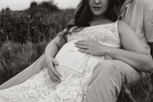 A romantic black and white photo series showing a couple in white clothing sitting together in a grassy field.