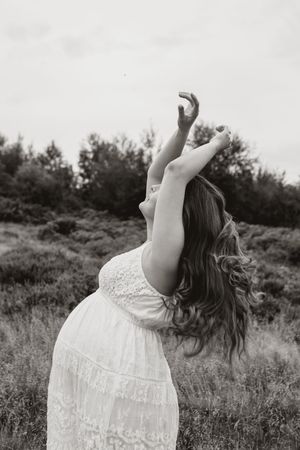 A series of black and white photos showing a woman in a white lace dress dancing freely in a grassy field.
