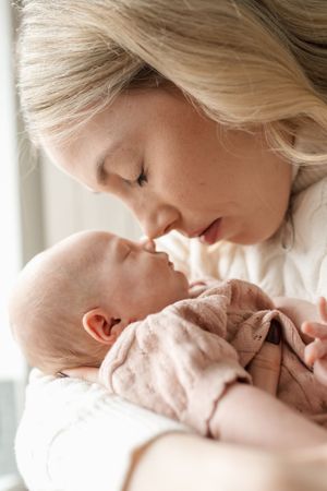 A tender moment captured in soft lighting as a parent lovingly kisses their sleeping newborn baby.