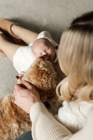 A person wearing a cream sweater lies on a couch with a fluffy brown dog in a series of cozy poses.