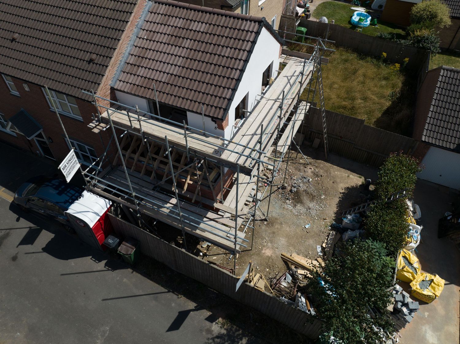 Aerial view of residential construction site with scaffolding and building materials.